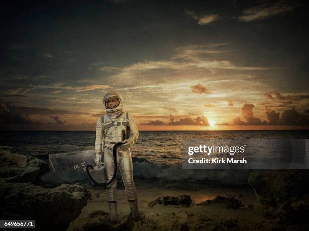 caucasian astronaut standing on beach at sunset - planet collision stock-fotos und bilder