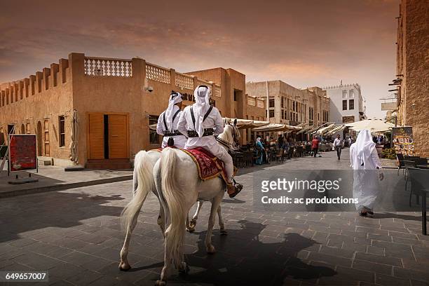 men riding horses on doha street, doha, qatar - doha foto e immagini stock