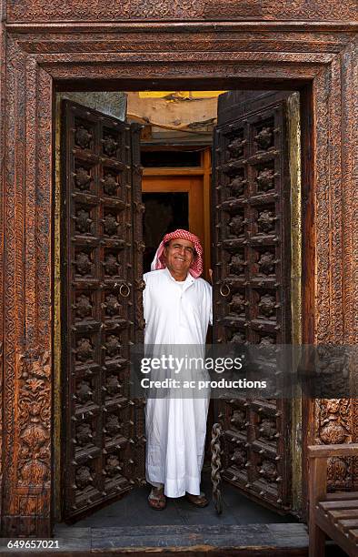 smiling man opening ornate doors - welcome to qatar stock pictures, royalty-free photos & images
