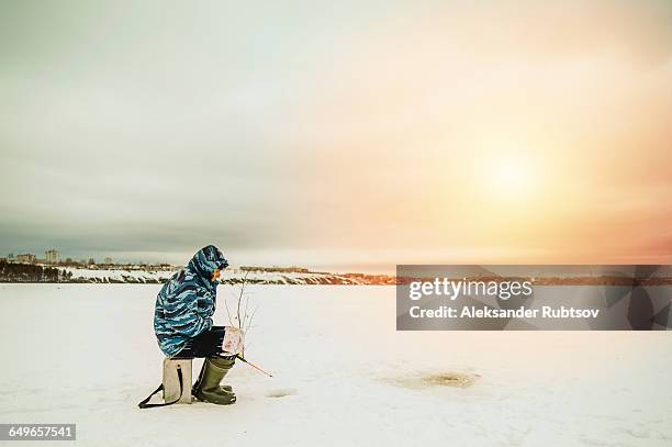 man ice fishing in frozen lake - ice fishing stock pictures, royalty-free photos & images