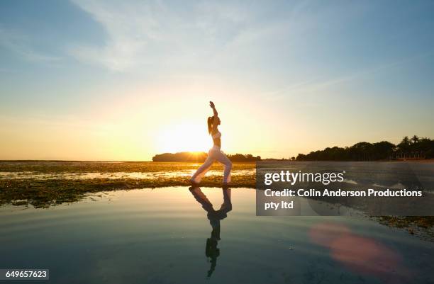 pacific islander woman practicing yoga near rippling water - nusa dua stock pictures, royalty-free photos & images