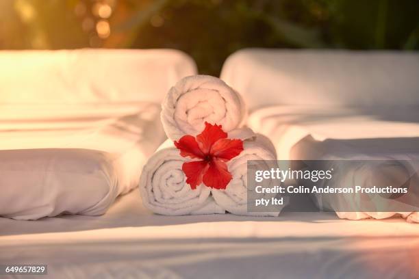 flower in towel rolls on massage table - bali massage stock-fotos und bilder