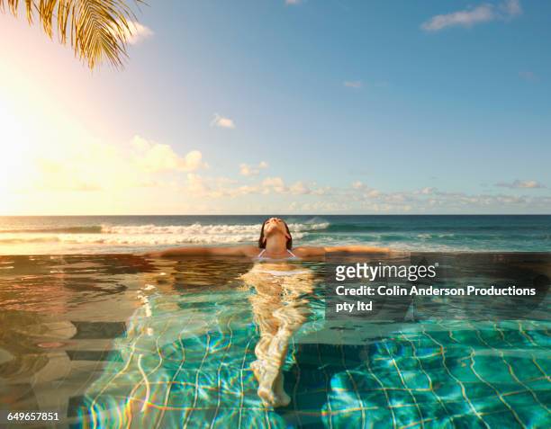 pacific islander woman laying in swimming pool - luxury travel stock-fotos und bilder