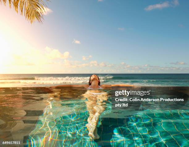 pacific islander woman laying in swimming pool - resort enjoy ストックフォトと画像