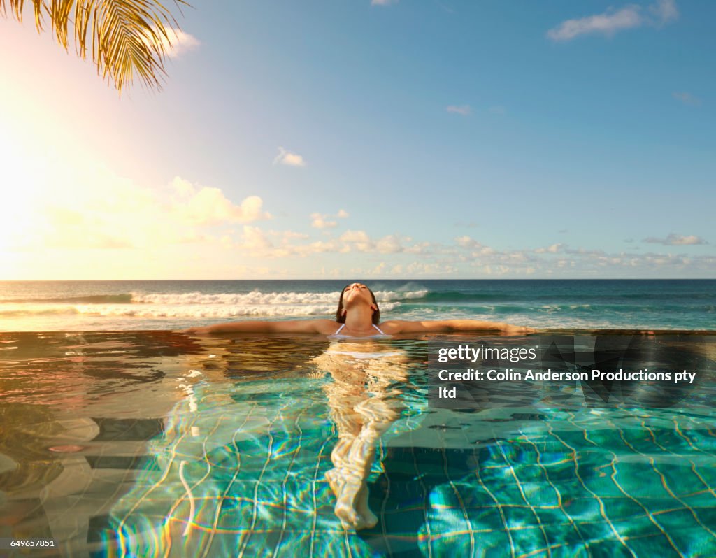 Pacific Islander woman laying in swimming pool