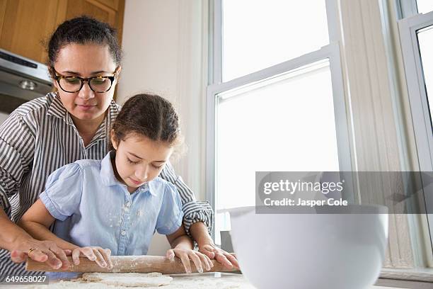 mother teaching daughter to bake in kitchen - rollende keukens stockfoto's en -beelden