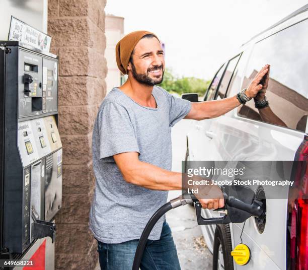 hispanic man pumping gas - fare il pieno di benzina foto e immagini stock