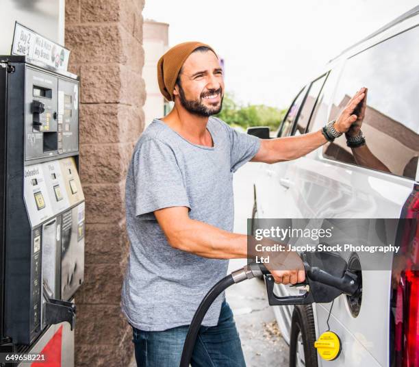 hispanic man pumping gas - ガソリンスタン�ド ストックフォトと画像