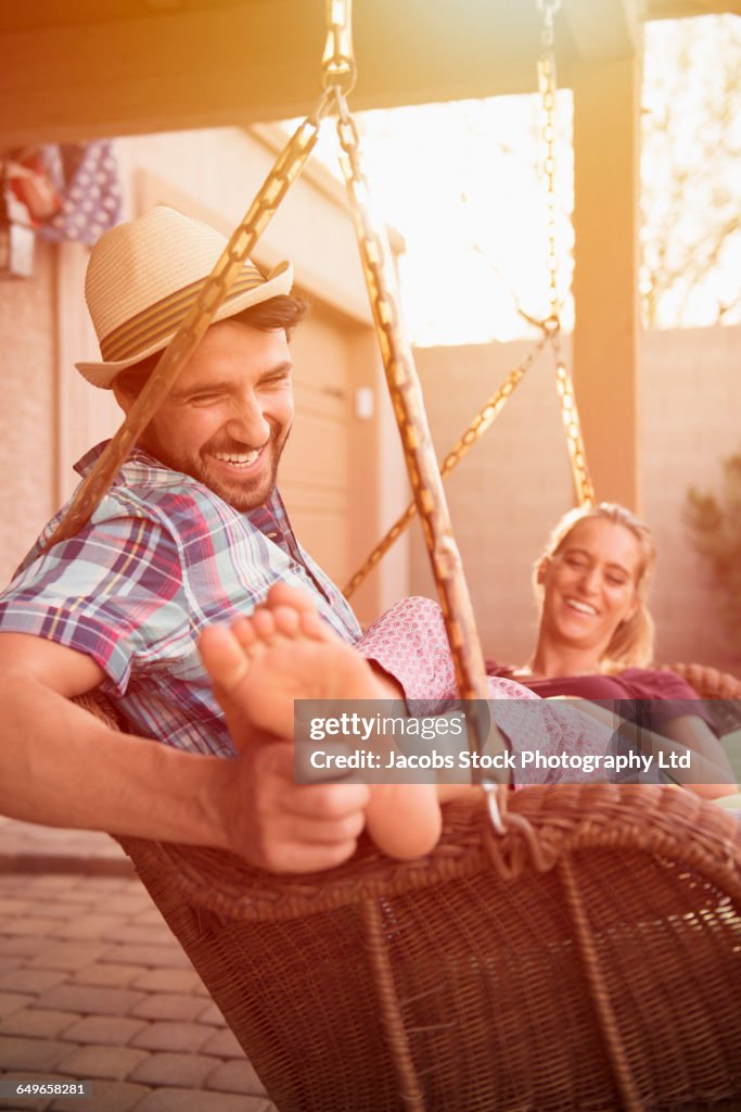 Hispanic couple relaxing in porch swing