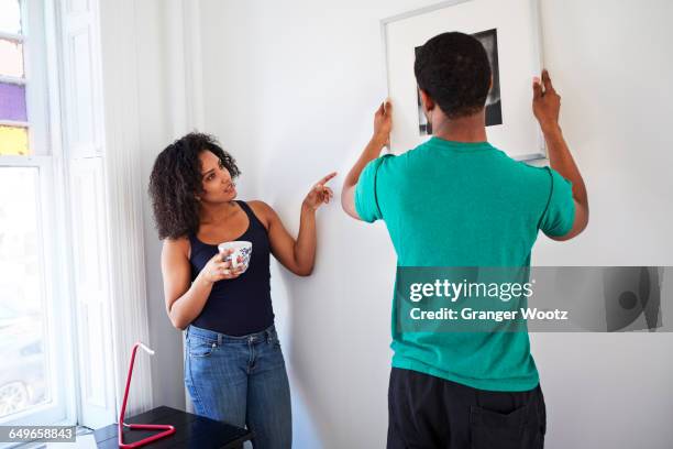 couple hanging picture in new apartment - new boyfriend stock pictures, royalty-free photos & images