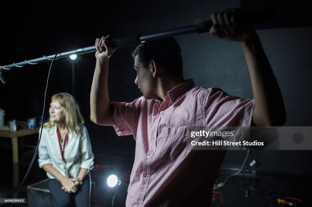 Crew member holding boom microphone on set