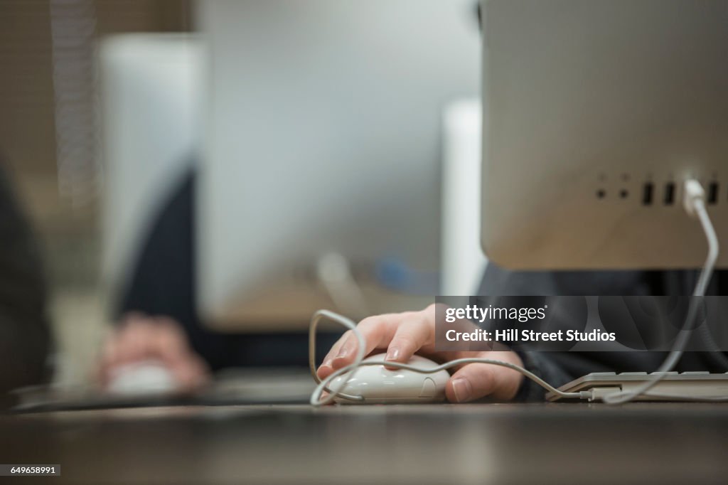 Close up of student using computer mouse in classroom