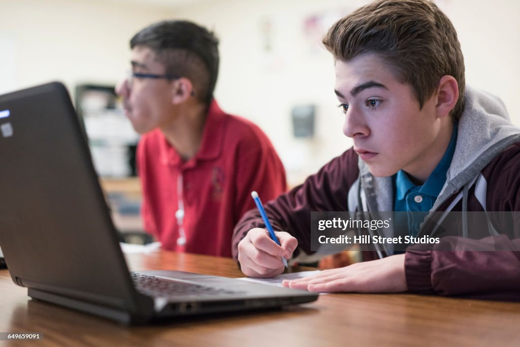 Student writing notes from laptop in classroom