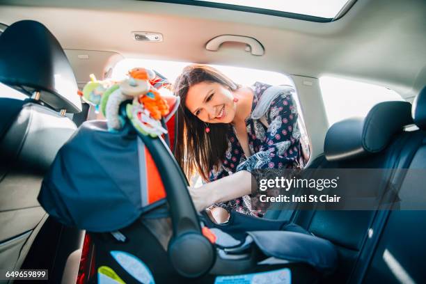 hispanic mother fastening car seat in car - pregnant woman car stock pictures, royalty-free photos & images