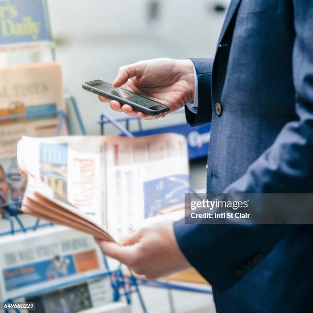 caucasian businessman using cell phone at newspaper stand - news 2015 stock pictures, royalty-free photos & images