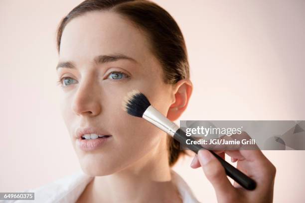 woman having makeup applied by stylist - makeup brush stock-fotos und bilder