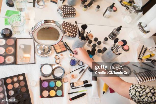 hispanic woman selecting makeup from table - make up table stock pictures, royalty-free photos & images