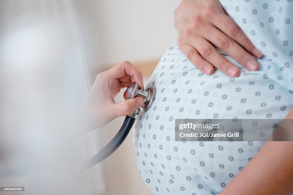 Doctor listening to belly of pregnant woman