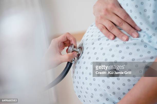 doctor listening to belly of pregnant woman - prenatal care stock pictures, royalty-free photos & images
