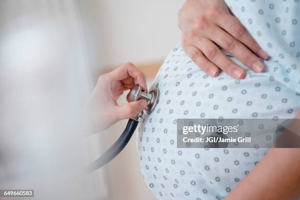 doctor listening to belly of pregnant woman - gravid imagens e fotografias de stock