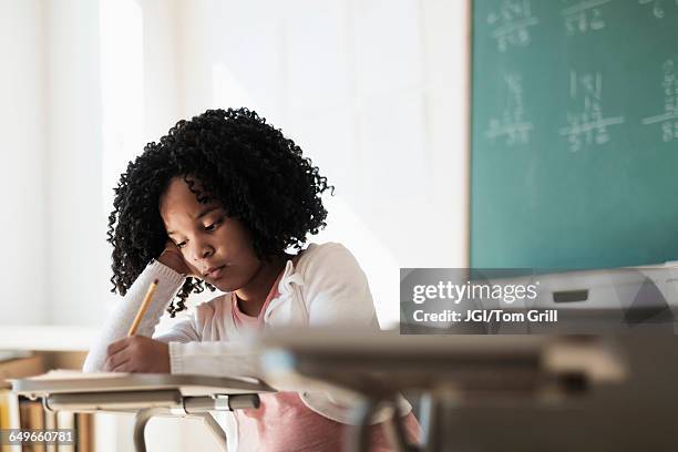 african american student writing in classroom - niña en edad escolar fotografías e imágenes de stock