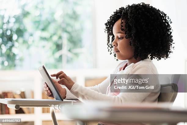african american student using digital tablet in classroom - kids modern school life stock-fotos und bilder