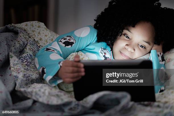 african american girl using digital tablet in bed - watching ipad stock pictures, royalty-free photos & images