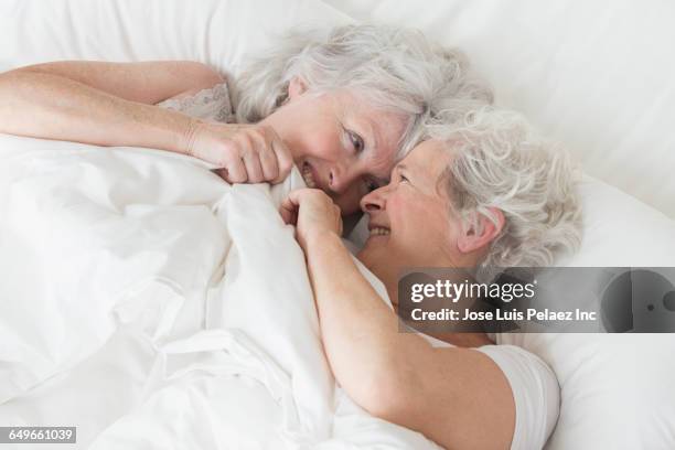 older caucasian lesbian couple laying in bed - lesbian bed stock pictures, royalty-free photos & images