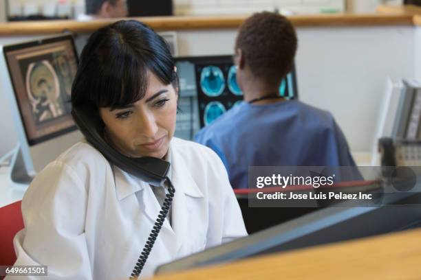 hispanic doctor talking on telephone in hospital - multitasking nurse stock pictures, royalty-free photos & images