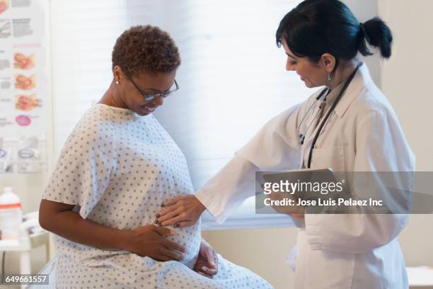 doctor checking belly of pregnant patient in hospital - prenatal care stock pictures, royalty-free photos & images