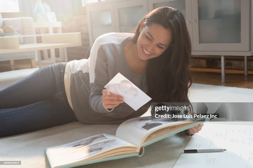 Hispanic woman placing photos in photo album