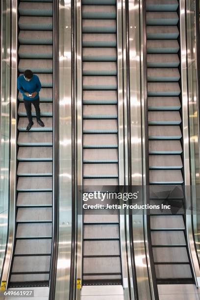 mixed race businessman using cell phone on escalator - rolltreppe von oben stock-fotos und bilder