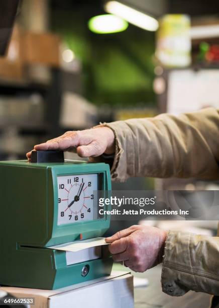caucasian worker punching time clock in warehouse - primo turno foto e immagini stock