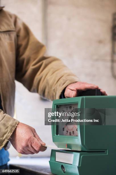 caucasian worker punching time clock - punching clock stock pictures, royalty-free photos & images