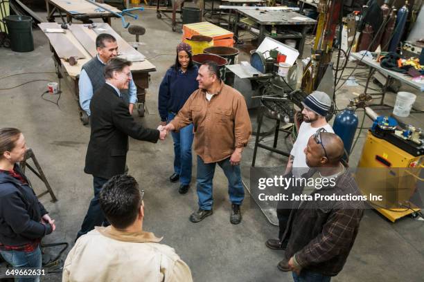 high angle view of worker and businessman shaking hands in workshop - respect awards inside stockfoto's en -beelden