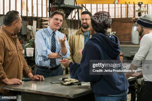 workers and businessman talking in workshop - metal workshop stockfoto's en -beelden