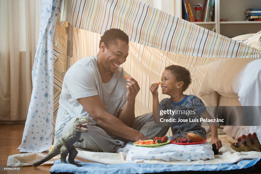 Father and son eating in blanket fort