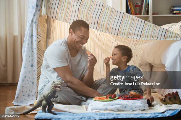father and son eating in blanket fort - fortress stockfoto's en -beelden