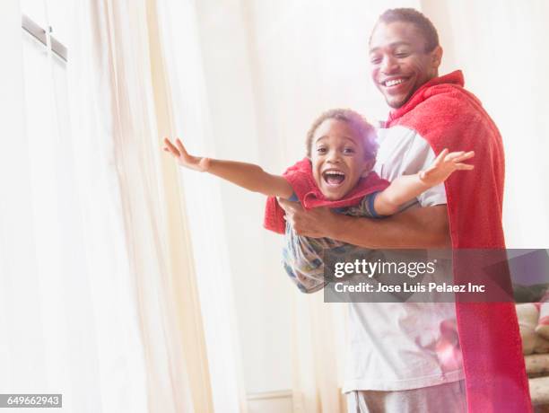 father and son playing dress-up in living room - zwarte mantel stockfoto's en -beelden