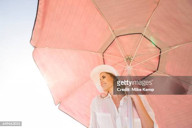 caucasian woman holding umbrella - rosa hut stock-fotos und bilder
