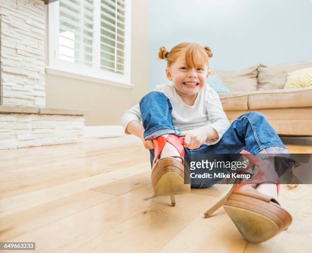 caucasian girl wearing adult shoes in living room - loose stock-fotos und bilder