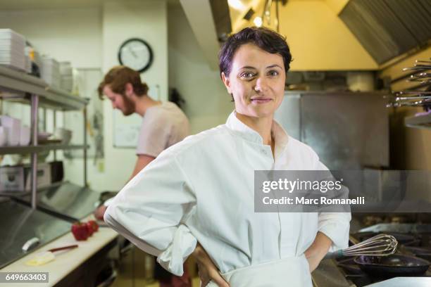 caucasian chef smiling in restaurant kitchen - young woman cooking in kitchen stock pictures, royalty-free photos & images