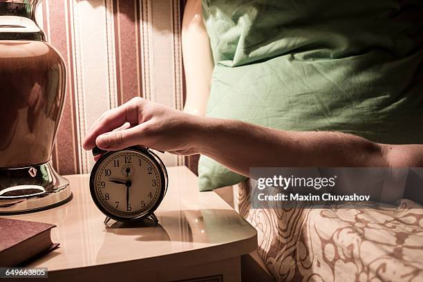 caucasian man turning off alarm clock - orologio sveglia foto e immagini stock