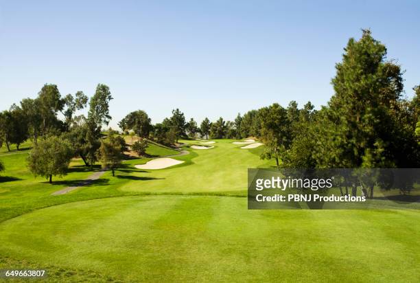 high angle view of golf course under blue sky - golf course stockfoto's en -beelden