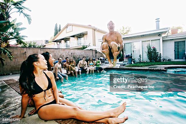 man jumping into swimming pool - cannonball pool stock pictures, royalty-free photos & images