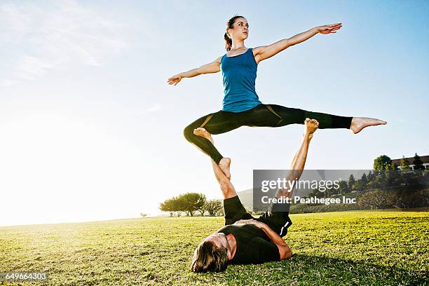 caucasian couple doing acro yoga in park - acroyoga stock pictures, royalty-free photos & images