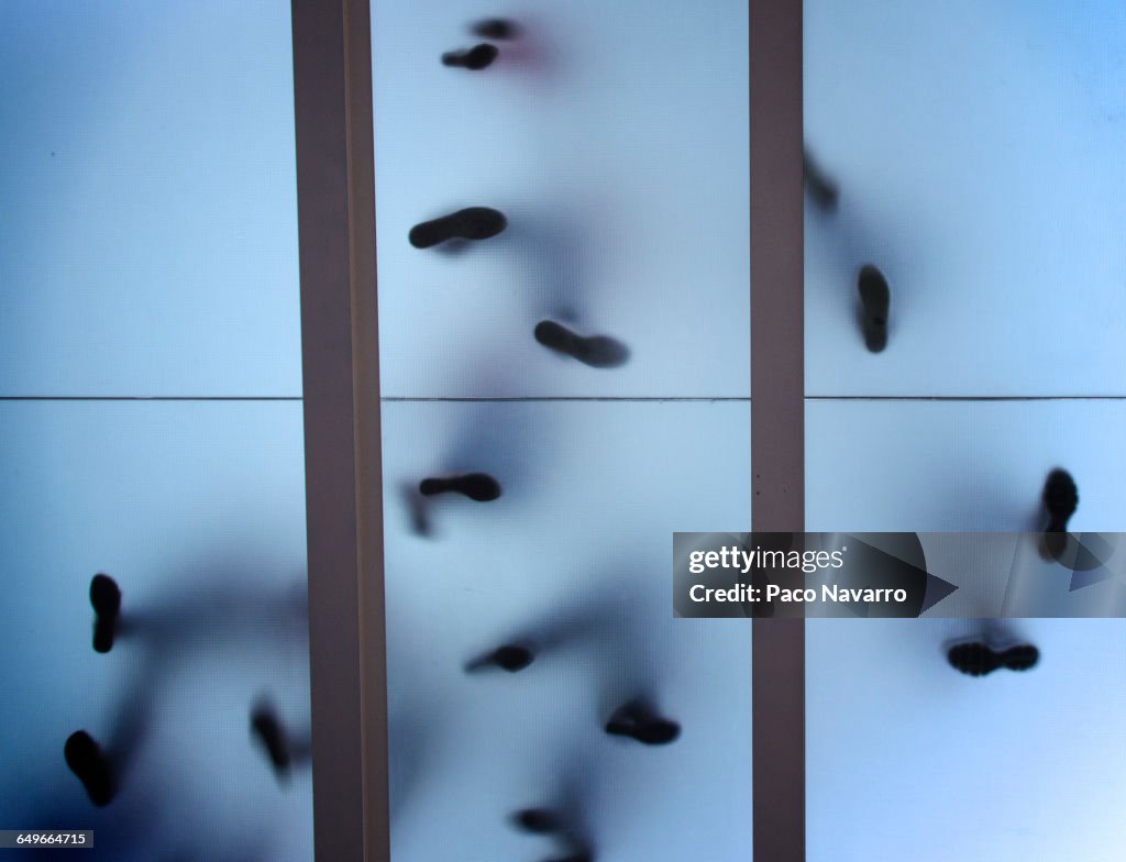 Silhouette of feet standing on glass ceiling