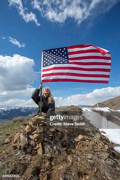 caucasian woman planting american flag on remote hilltop - vlag planten stockfoto's en -beelden