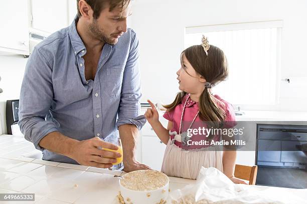 caucasian father and daughter eating cereal in kitchen - girl pointing stock-fotos und bilder