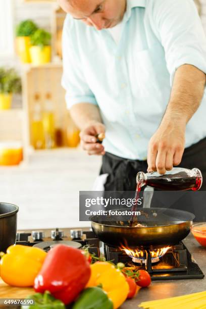 chef pouring red wine into frying pan - red cooking pan stock pictures, royalty-free photos & images